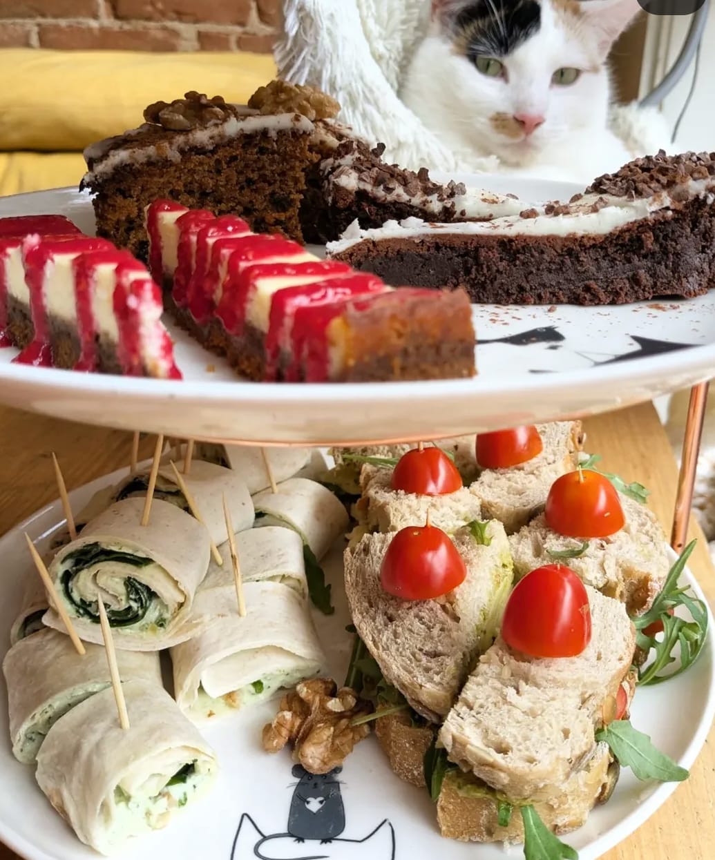 Etagère met zoete en hartige lekkernijen, met een kat op de achtergrond